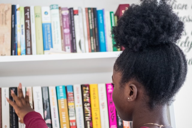 A young girl looking at books on a bookshelf